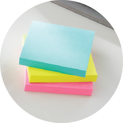 Blocs de notas azul, amarillo y rosa apilados.
